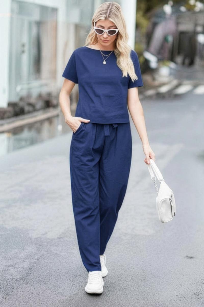 Woman wearing navy blue cotton linen set with short sleeve top and drawstring pants walking outdoors
