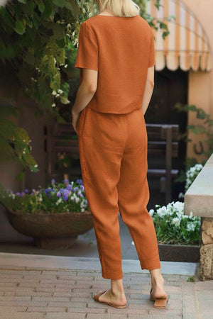Woman wearing orange cotton linen set with short-sleeve top and straight-leg pants outdoors