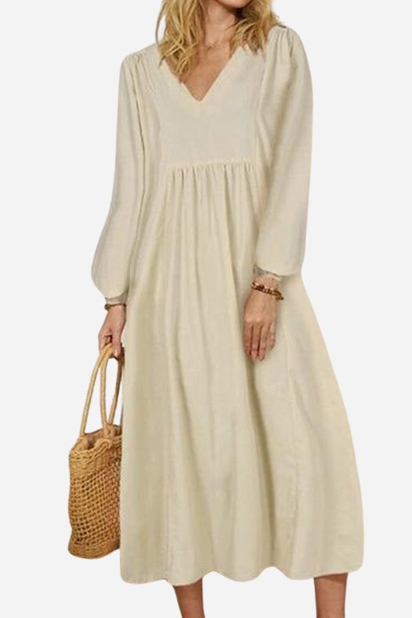 Woman wearing beige midi long sleeve spring dress with V-neck and loose fit holding woven bag