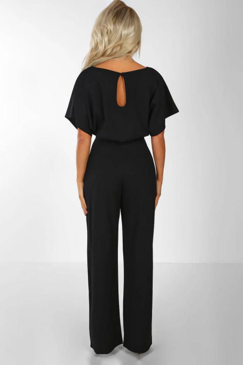 Woman wearing a black chic short-sleeved wide-leg jumpsuit with back keyhole detail and belt.