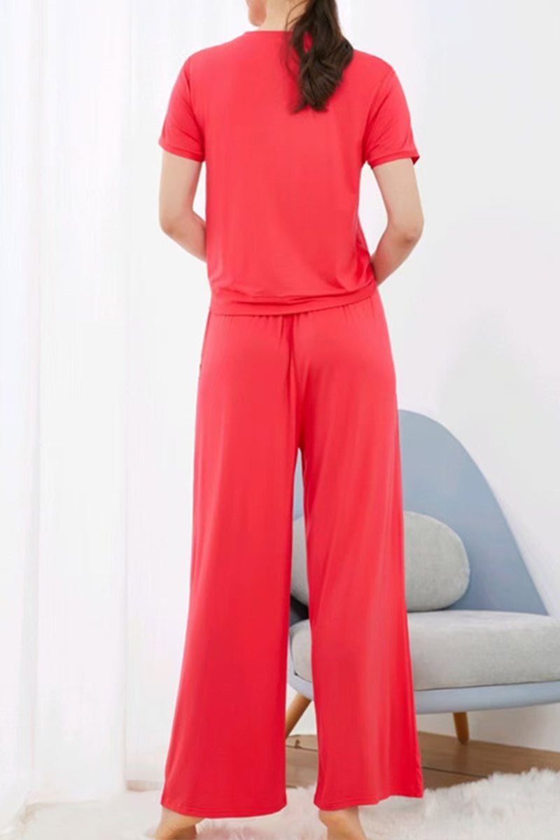 Woman wearing red bamboo fiber pajama clothes with short sleeves and wide-leg pants in a modern room.