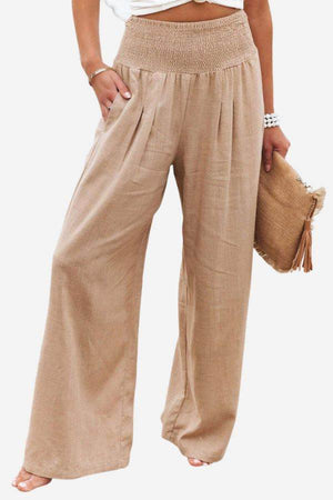 High-waist cotton linen palazzo pants in beige with wide legs and pockets, styled with a white top and beige clutch.