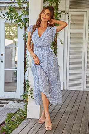 Woman wearing Elegant Blossoms Boho Maxi Dress with floral pattern, V-neck, ruffled sleeves, and belted waist standing on porch.