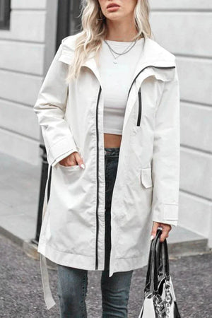 women wearing white water-resistant windbreaker trench jacket with black zipper and belt outdoors