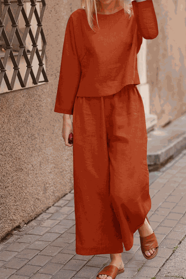 Woman wearing loose solid color two-piece set in rust with wide-leg pants and long sleeve top
