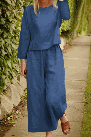 Woman wearing a loose solid color blue two-piece set with long sleeves and wide-leg pants walking outdoors