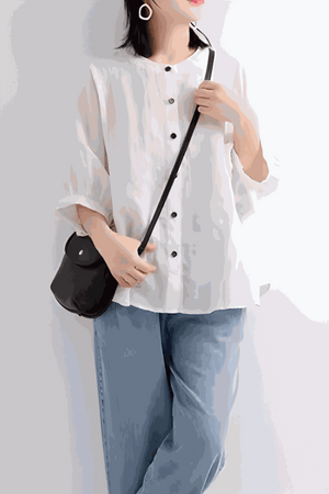 Woman wearing relaxed loose breathable white linen blouse with black buttons and blue jeans carrying a black purse