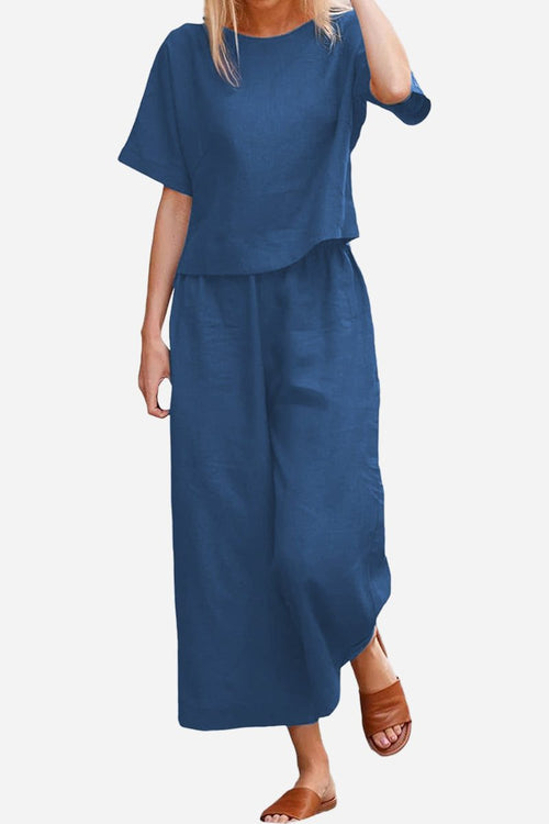 Woman wearing navy blue loose fit co-ord set with short sleeves and wide-leg pants paired with brown sandals