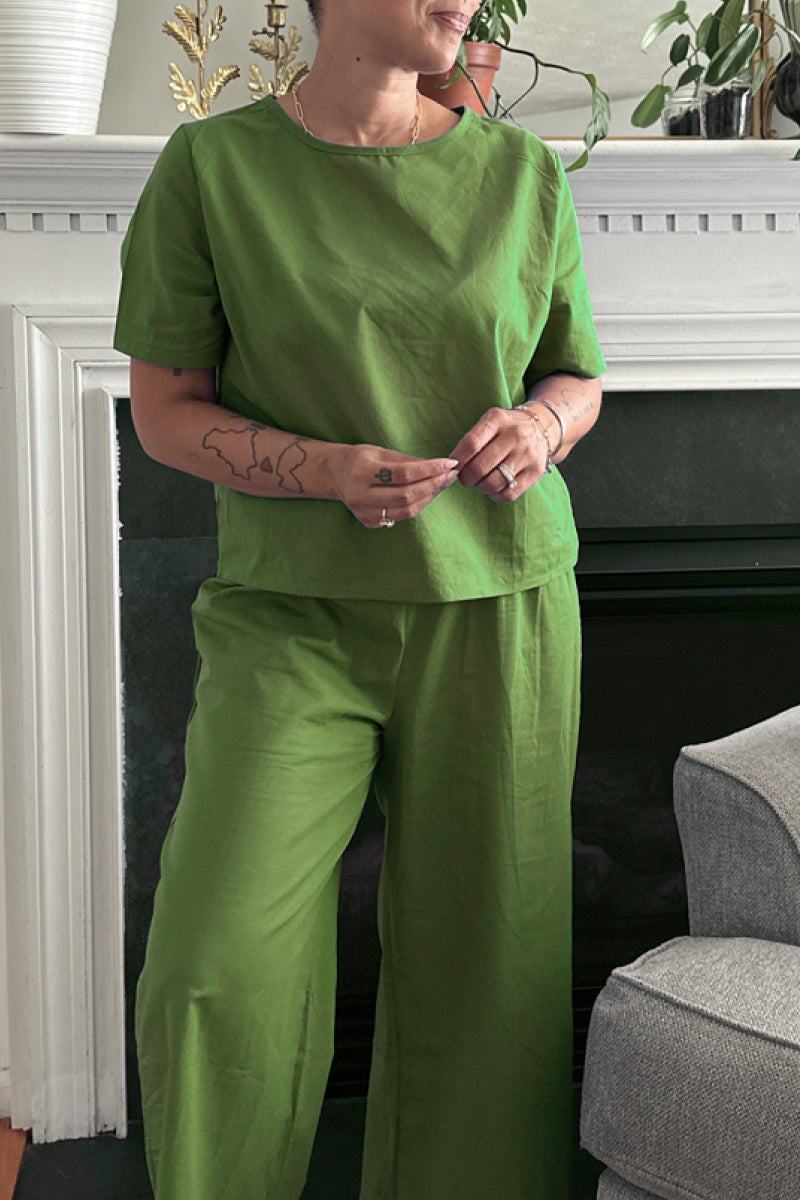 Woman wearing green loose fit co-ord set with short sleeves and wide-leg trousers indoors