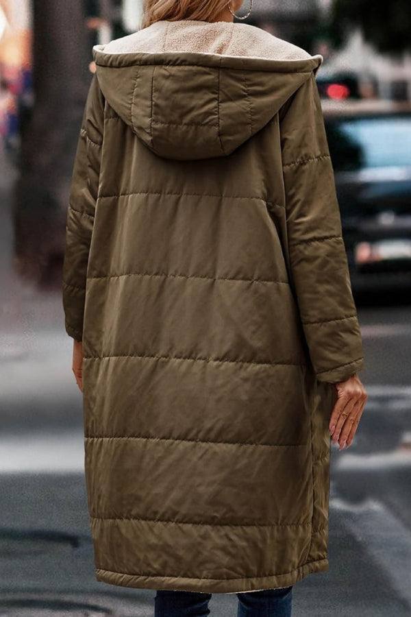 Back view of a woman wearing a long olive green Sherpa-lined hooded teddy coat on a city street.