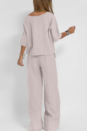 Woman wearing a light pink short-sleeved pullover and wide trouser matching set, shown from the back