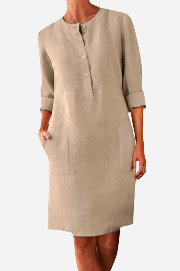 Khaki cotton dress with half-button front, rolled ¾ sleeves, and practical pockets.