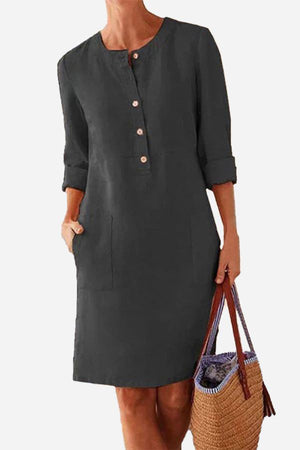 Black cotton dress with rolled 3/4 sleeves and front buttons, featuring pockets and a casual knee-length fit.