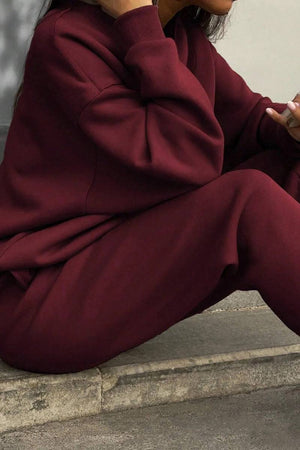 Woman wearing maroon cotton-blended two-piece tracksuit sitting outdoors