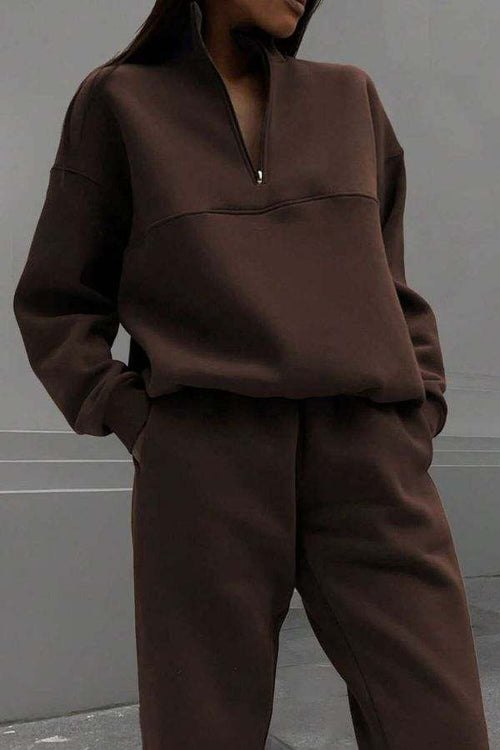 Woman wearing a brown cotton-blended two-piece tracksuit with high collar and deep zipper.