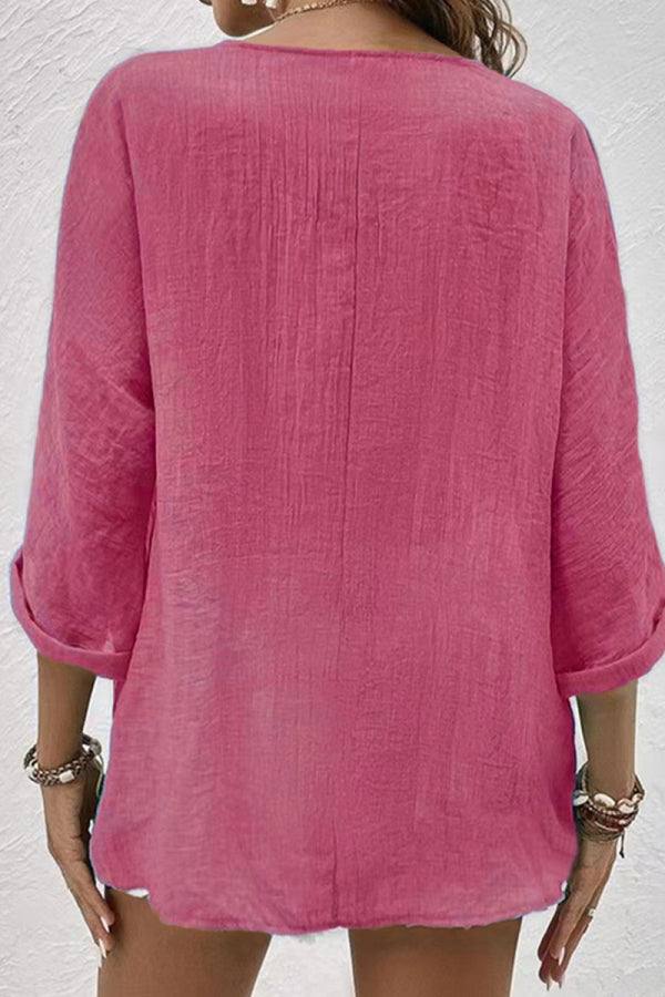Back view of a pink breezy button front tunic with rolled sleeves on a woman