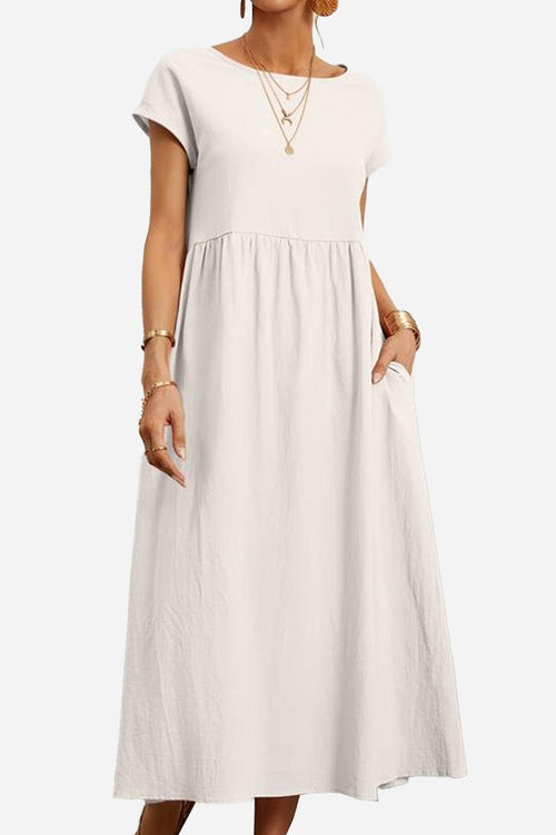 Woman wearing a white capped-sleeve voluminous pleated midi dress with pockets and layered necklaces