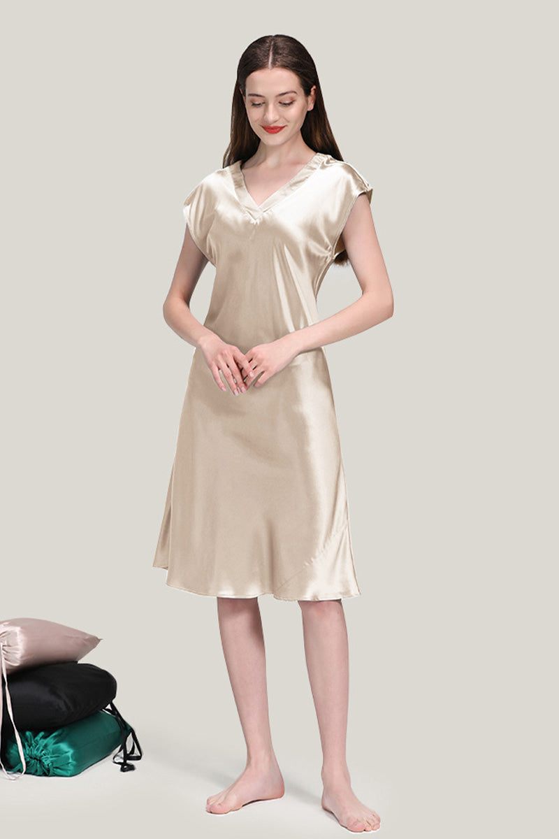 Woman wearing a luxurious beige Mulberry Silk V-Neck Nightgown standing barefoot against a plain background