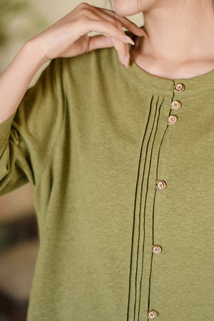 Close-up of a green Linen Cotton Classy eco-friendly shirt with wooden buttons and stitched detailing on a woman's upper body