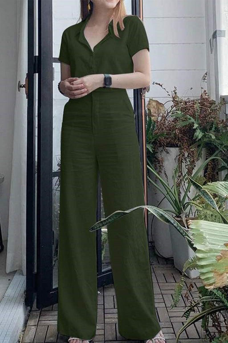 Woman wearing olive green linen-look set with short sleeves and wide-leg pants standing near glass door with plants
