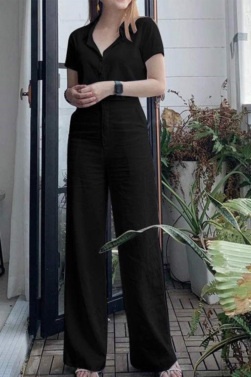 woman wearing black linen-look set with short-sleeve top and wide-leg pants standing indoors near plants