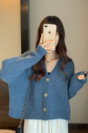 Woman wearing blue casual loose boxy cardigan with buttons taking a mirror selfie