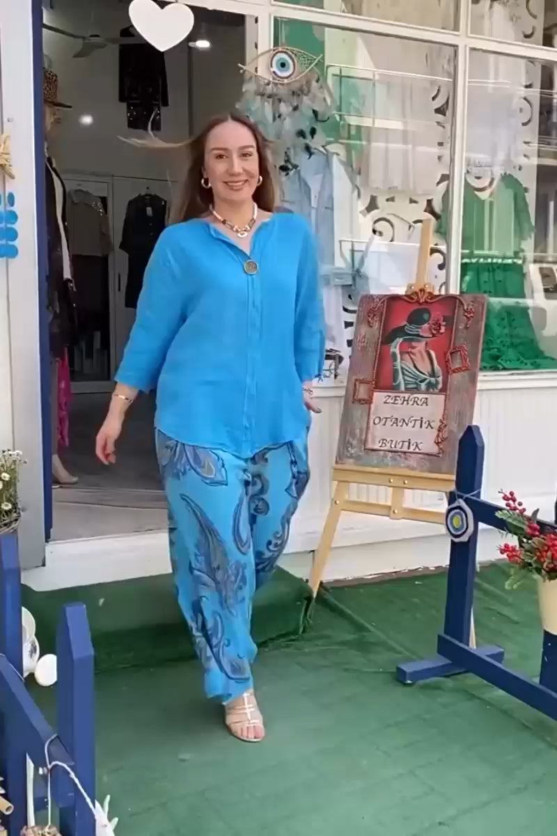 woman wearing vibrant fusion two-piece set with blue top and printed pants walking outdoors near storefront