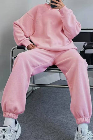 Pink comfy chic tracksuit with relaxed fit, long sleeves, and elastic cuffs, paired with white sneakers.