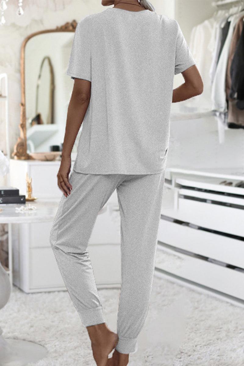 Woman wearing a gray ultra-soft two-piece loungewear set with short sleeves and jogger pants in a cozy modern bedroom interior