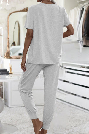 Woman wearing a gray ultra-soft two-piece loungewear set with short sleeves and jogger pants in a cozy modern bedroom interior
