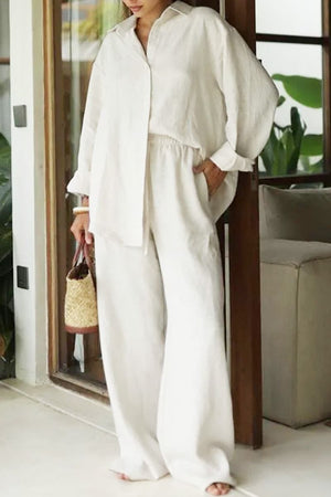 woman wearing white 100% cotton Wanderlust two piece set with long sleeves and wide pants indoors carrying woven bag