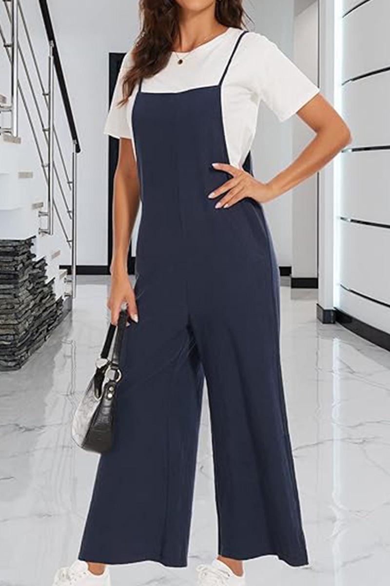 Woman wearing navy cotton blend comfort jumpsuit with white short sleeve top in modern indoor setting
