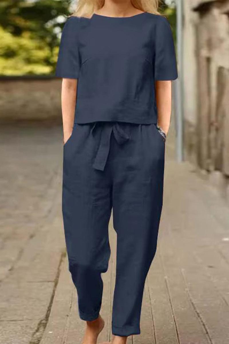 Woman wearing navy blue cotton-linen blend monochrome two-piece set with short sleeves and relaxed fit pants walking outdoors