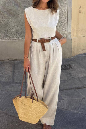 Woman wearing cotton-linen blend sleeveless crop top and wide-leg pants summer outfit with brown belt and straw handbag