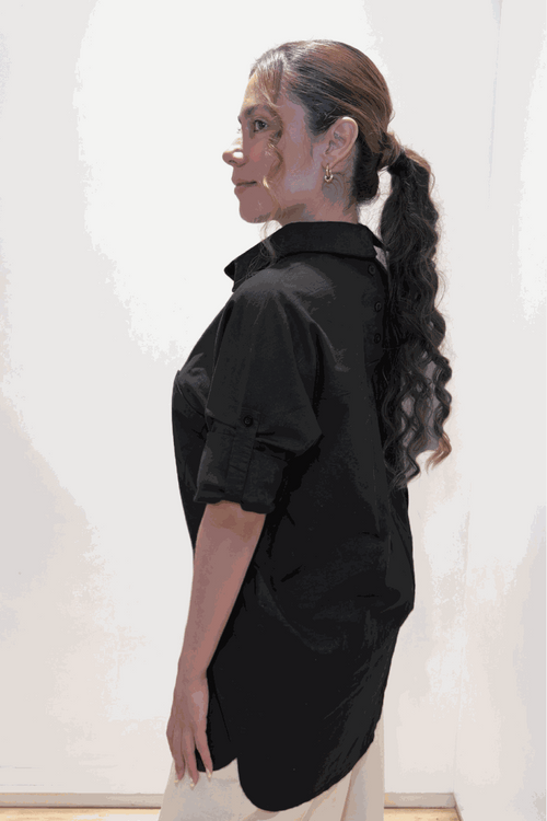 Woman wearing black oversized linen-leaved-in set shirt with rolled sleeves, side view