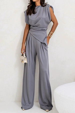 Woman wearing Manhattan Lines Draped two-piece gray set with asymmetrical draped sleeveless top and wide-leg pants.