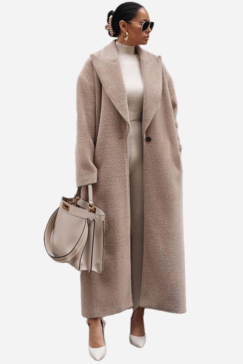 Woman wearing oversized teddy coat in beige with longline silhouette and oversized lapels, styled with matching outfit and handbag
