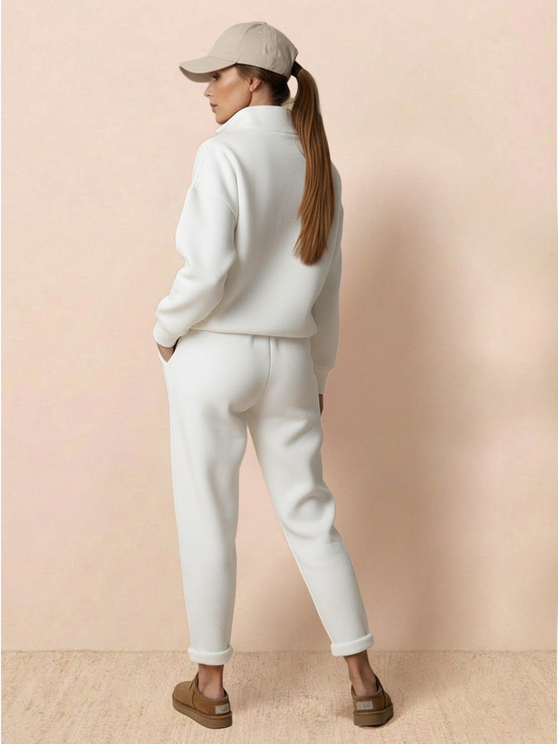 Woman wearing Warm & Easy Two-Piece Set white soft sweatshirt fabric with matching pants and beige cap standing against beige background