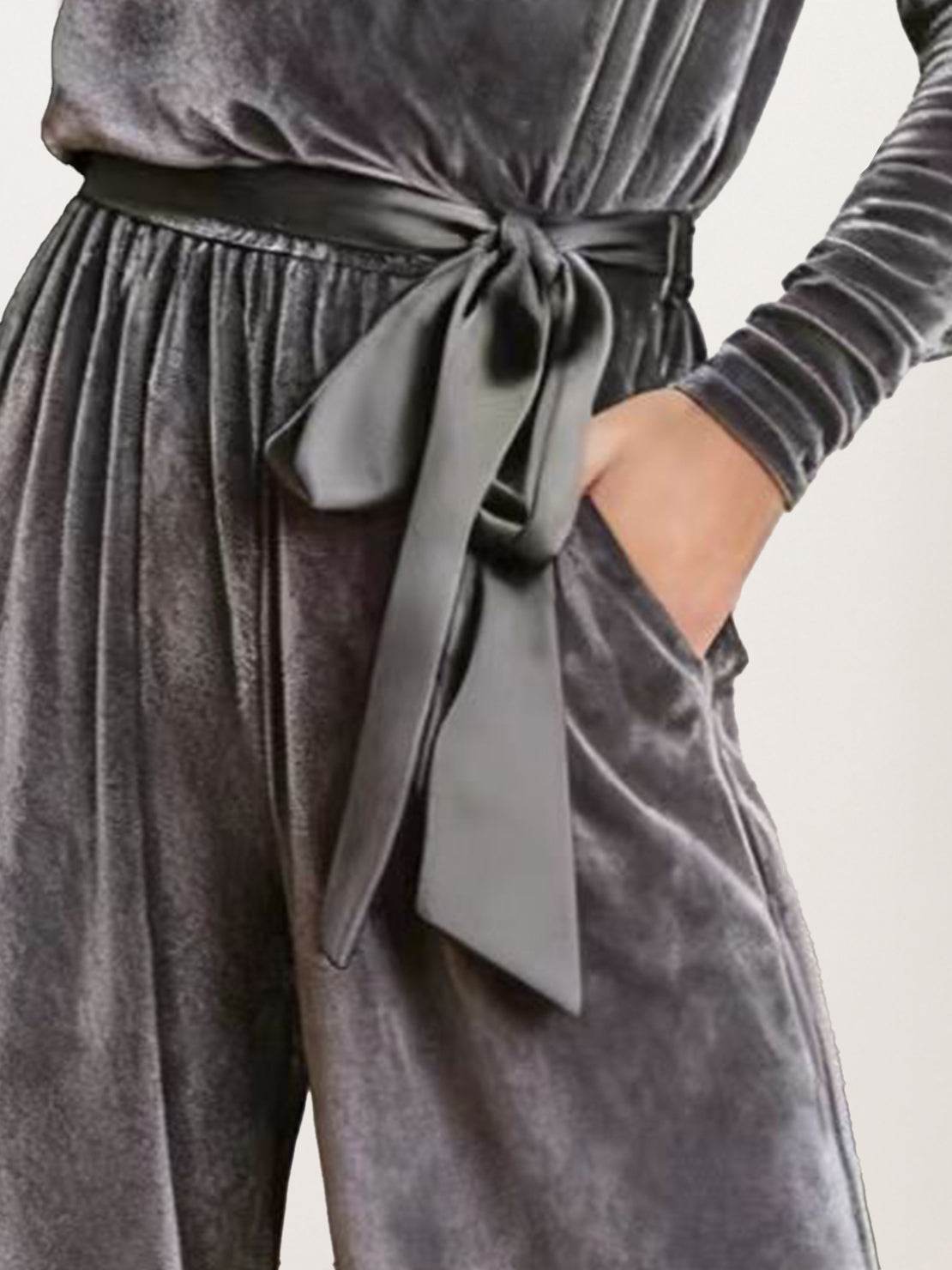 Woman wearing a deep V-neck velvet suit with long sleeves, removable waist tie, and wide-leg pants at an evening event