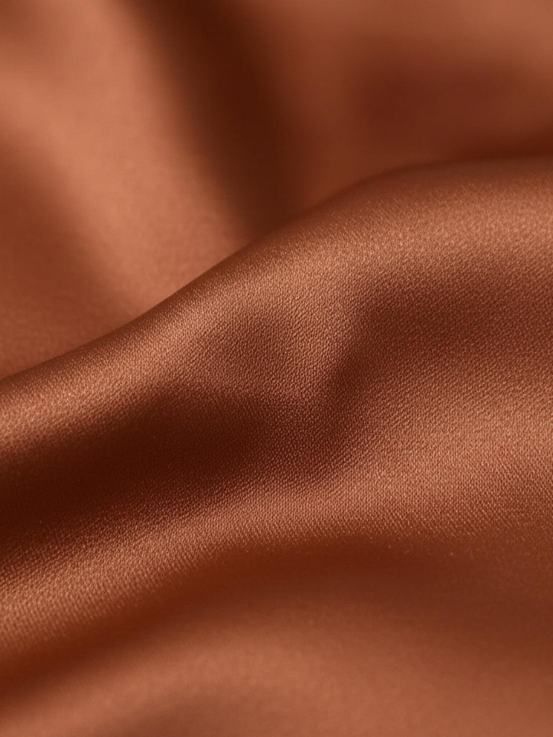 Silk-finish button front shirt with smooth fabric, traditional collar, relaxed fit, and curved hem.