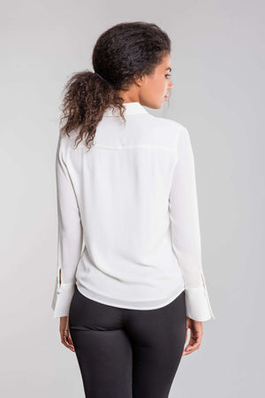 Back view of a woman wearing a white Bayam Blouse and black pants