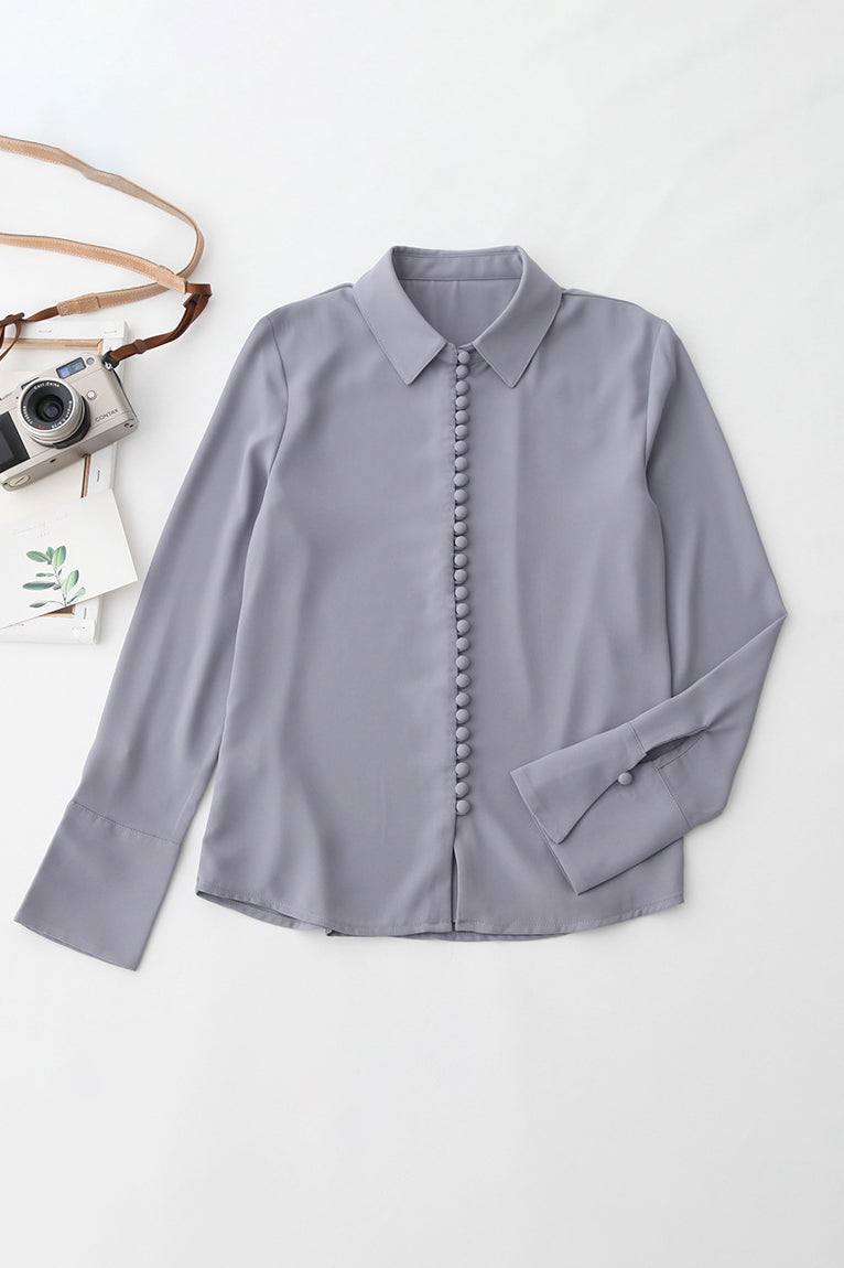 Bayam Blouse in soft gray with button-down front and classic collar, long sleeves, made of 100% polyester.