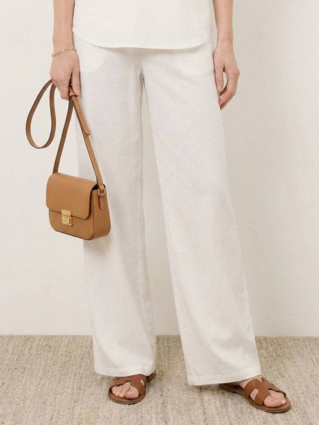 Mature woman wearing lightweight linen top with V-neck and three-button detail in light khaki