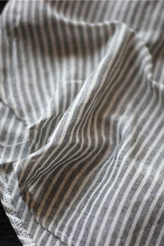 Close-up of striped linen blend fabric with gray and white stripes and gauzy texture