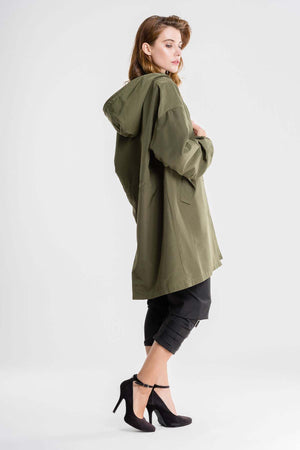 Woman wearing olive green water-resistant oversized hooded windbreaker rain jacket with black pants and heels