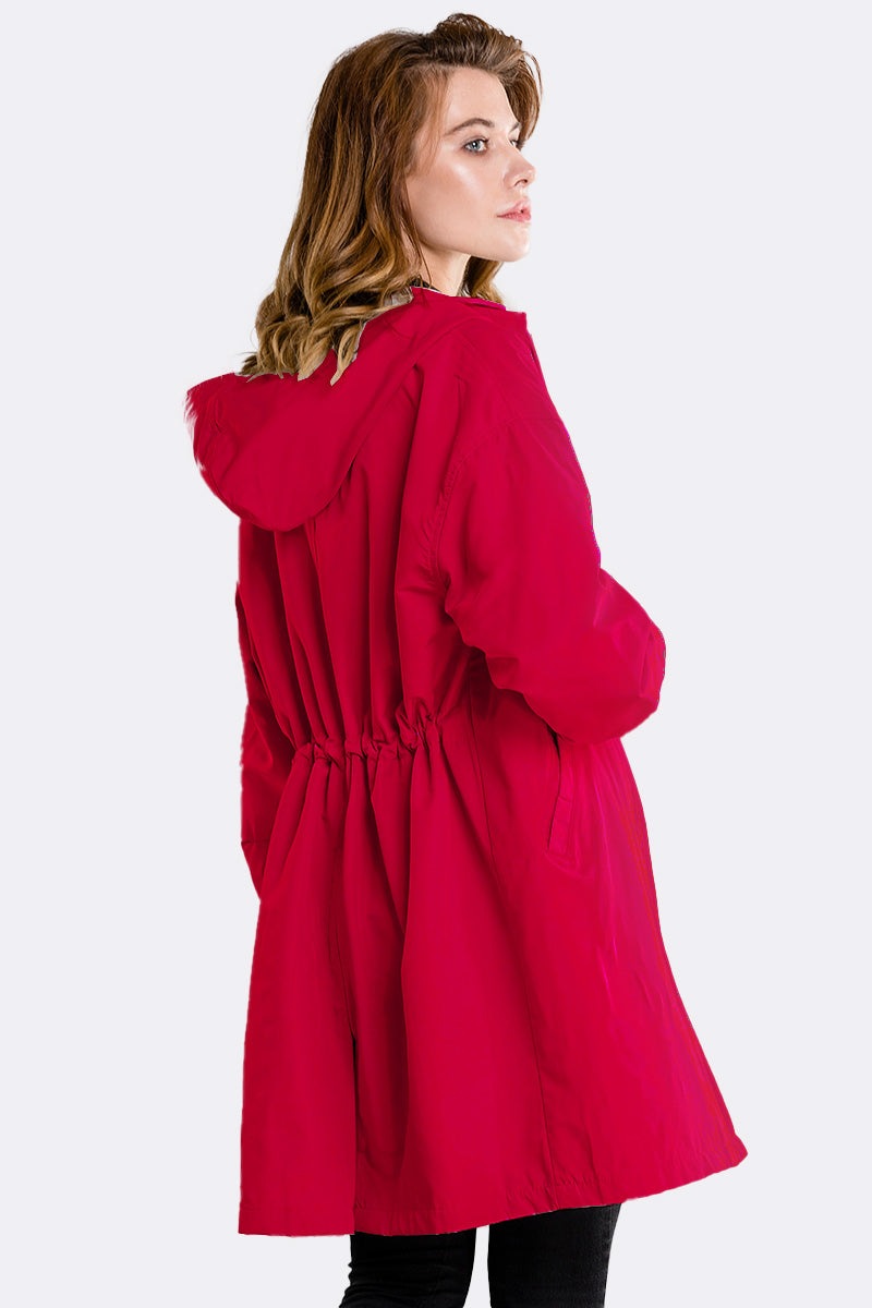 Woman wearing a cherry red water-resistant oversized windbreaker with hood and adjustable waist