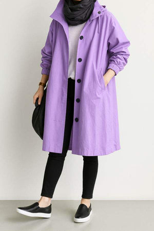 Water-resistant oversized purple hooded windbreaker rain jacket worn with black leggings and slip-on shoes