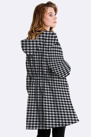 Water-resistant oversized windbreaker rain jacket with hood in black and white houndstooth pattern worn by woman side view