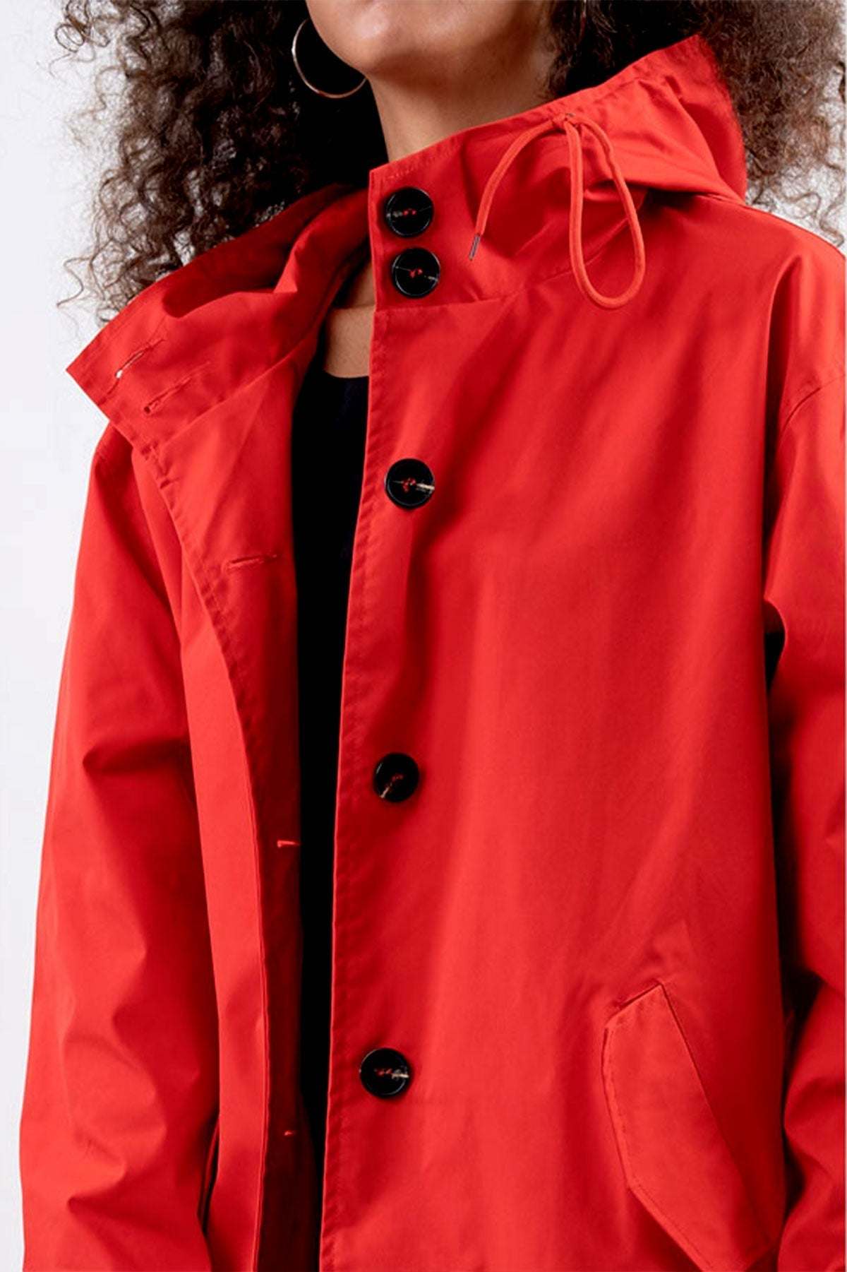 Red water resistant oversized hooded windbreaker with black buttons and pockets.