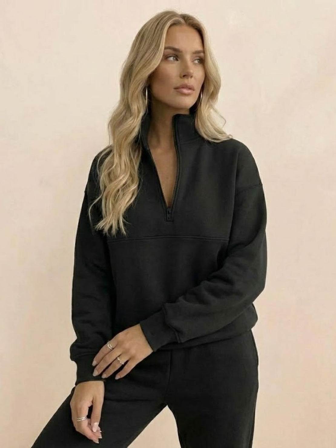 Woman wearing a cotton-blended two-piece tracksuit with high collar and zipper, styled for casual comfort and confidence.